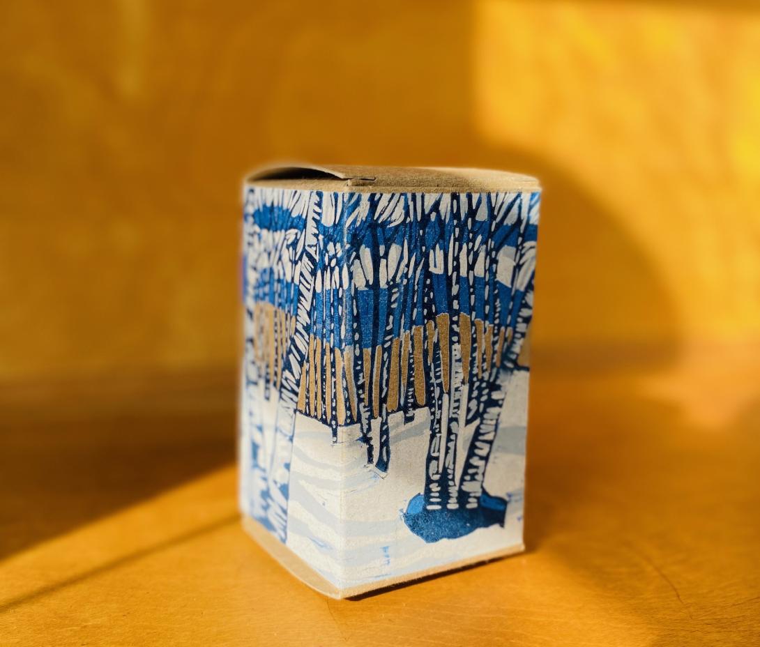 Cardboard box printed with a linocut image of birch trees.
