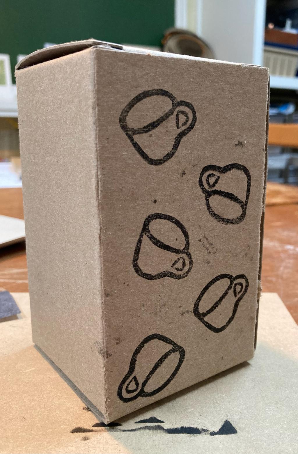 A brown box, with 5 versions of the lino coffee cup printed on it, in various orientations.