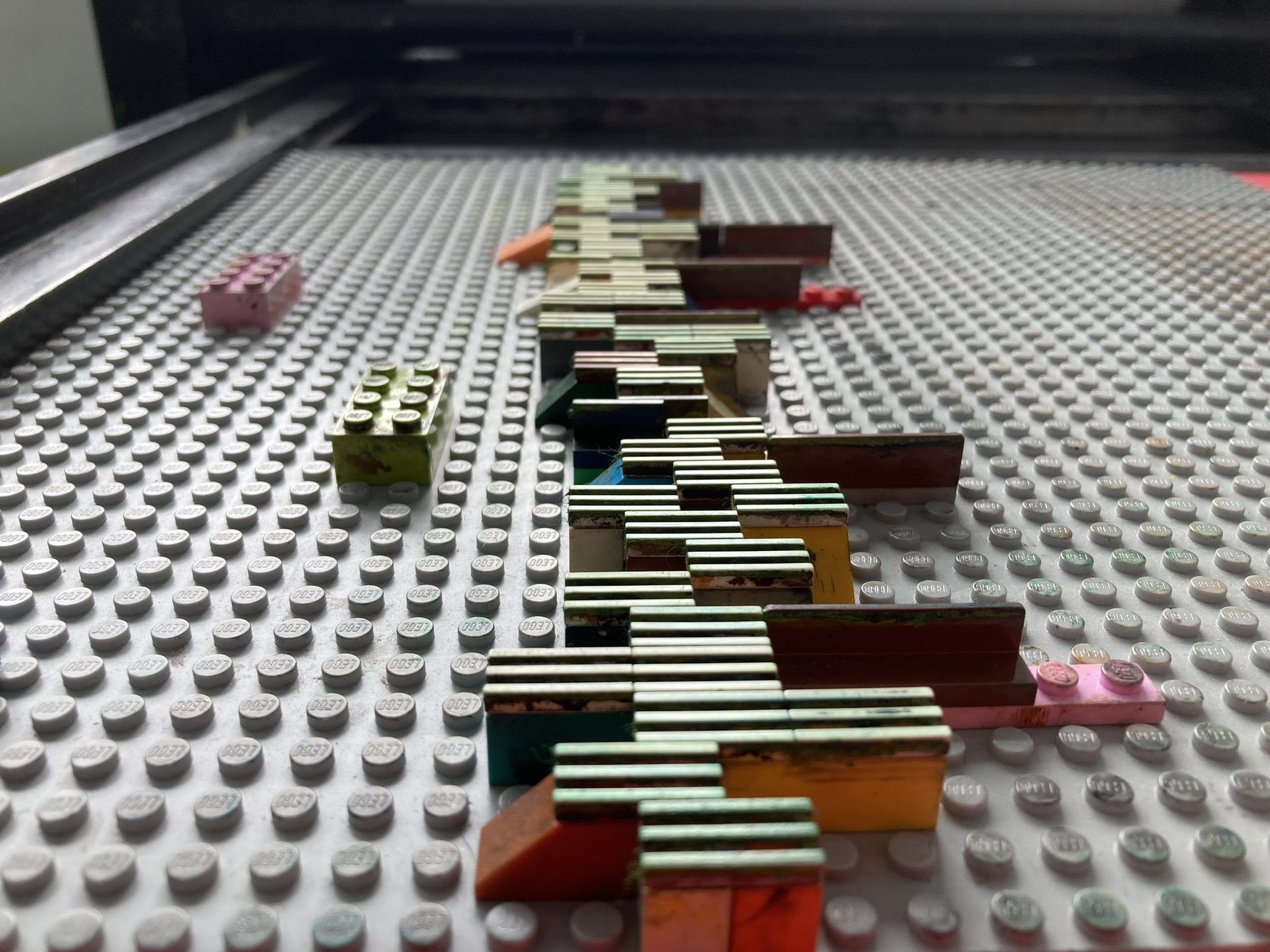 Lego pieces on a base plate, arranged to be printed on a letterpress.