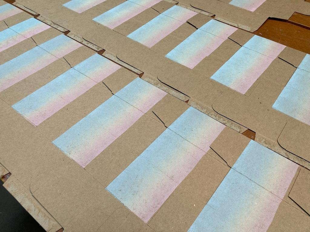 A pile of all of the rainbow roll-printed boxes set to dry on a table.