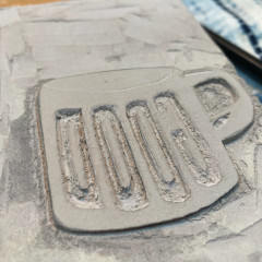 Lino block carved with "Good" on a coffee mug.