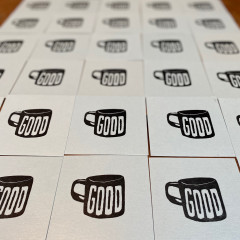 Blue cards printed with "Good" on a coffee mug, set to dry.