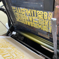 The chase of type in the printing press, inked with yellow ink