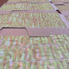 Boxes laid out to dry, printed with overlapping type of many different colours