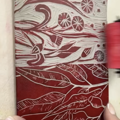 A lino block being rolled with red ink