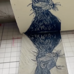 Inked lino block of a hare bring printed onto paper