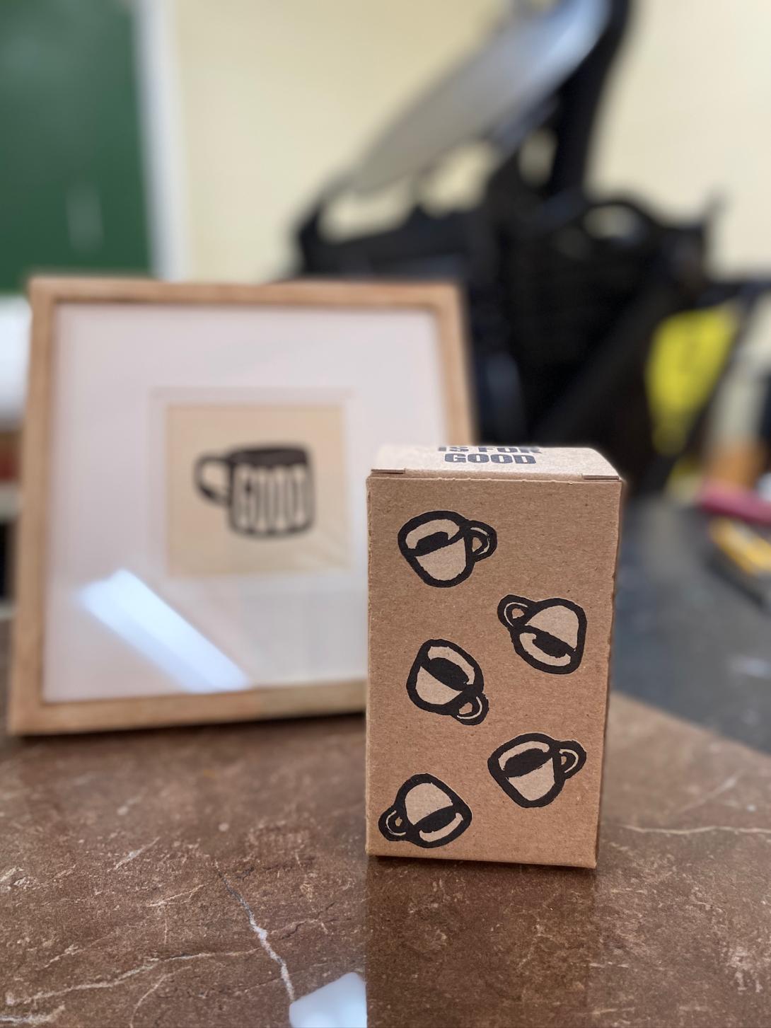 The "coffee" box, showing five espresso cups appearing to fall from the sky. In the background is a framed print of a coffee mug with GOOD printed on it.