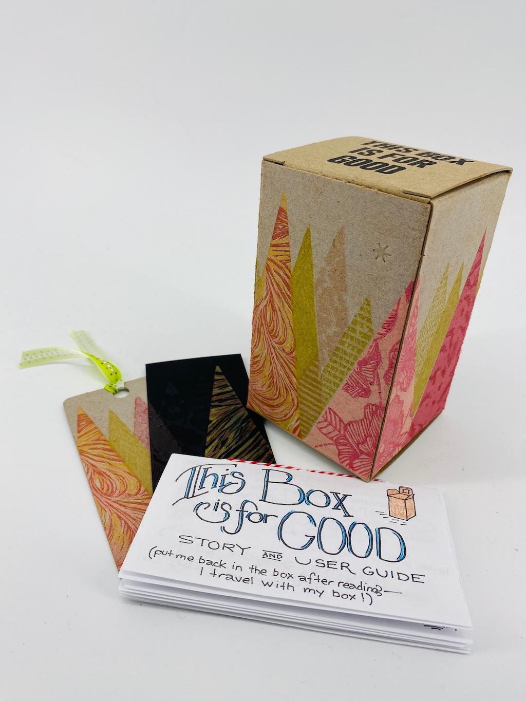 The "trees" box, showing gold, pink, and red abstract triangles printed on a brown boxboard box, with "This Box is for Good" printing on the top flap.