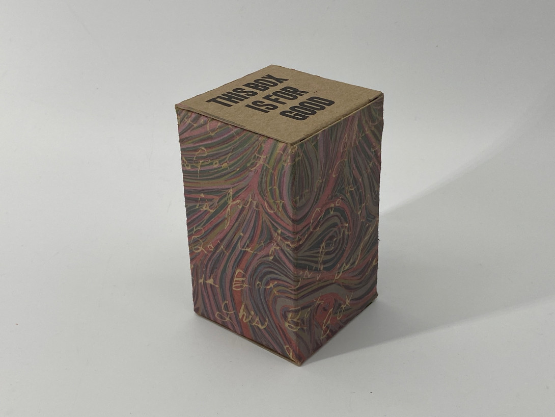 A brown cardboard box on a white background. Printed on the box is an abstract pattern of swirling colors, resembling marbled paper