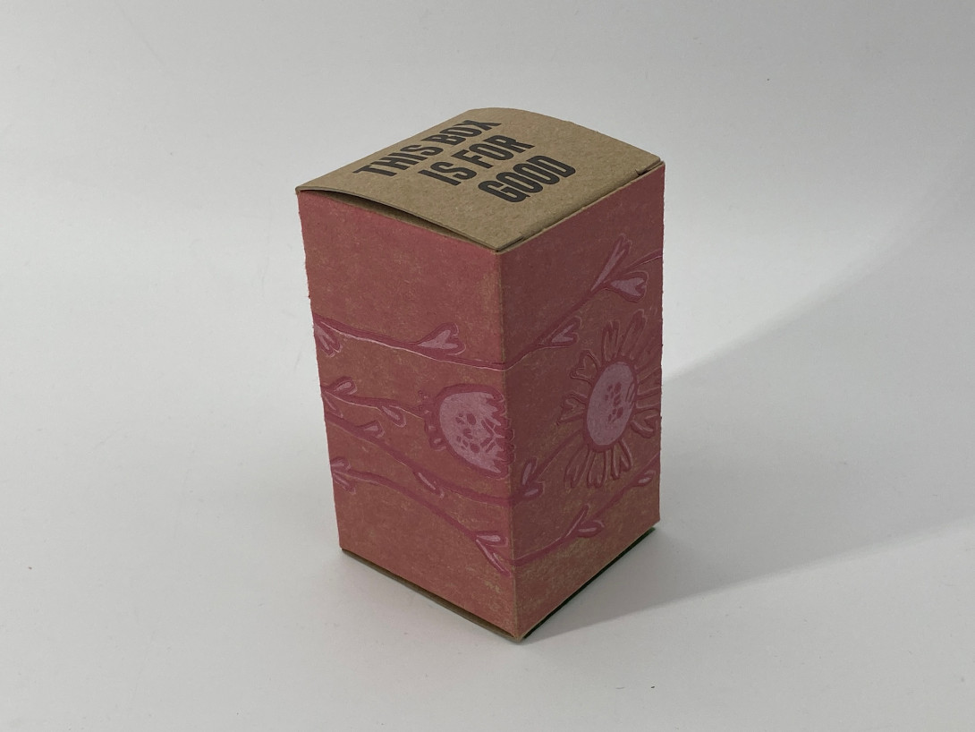 A brown cardboard box on a white background. Printed on the box, and pink, our cartoon like shapes of wildflowers