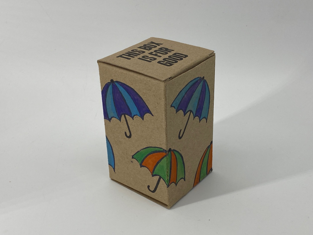A brown cardboard box on a white background. Printed on the box, and multiple colors, are floating umbrellas