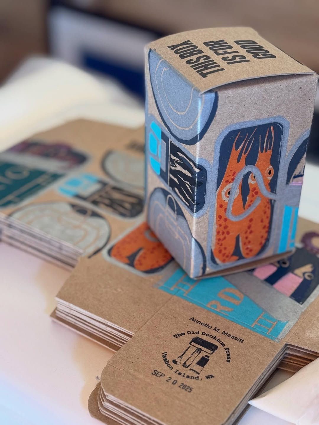 The printed box, assembled, sitting on a stack of folded boxes.